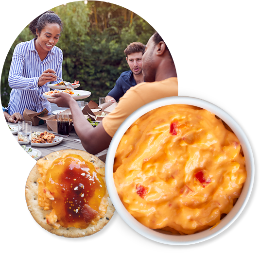 three people at a picnic sharing food made with prices cheese.